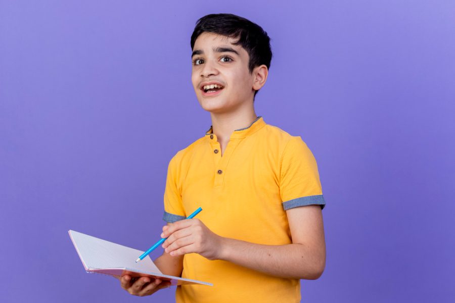 impressed-young-caucasian-boy-holding-note-pad-pencil-isolated-purple-wall-with-copy-space