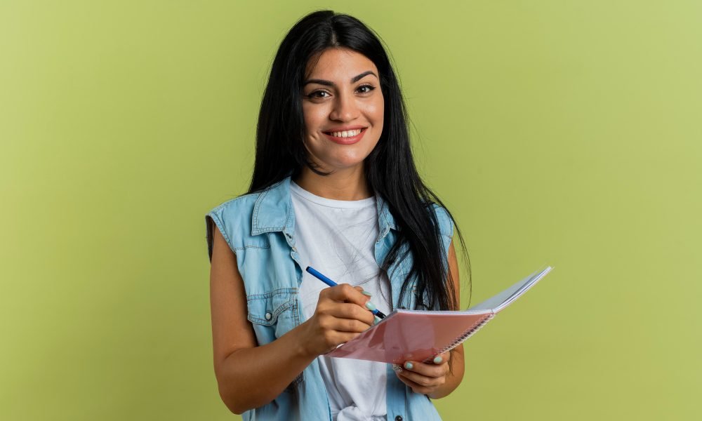 smiling-young-caucasian-woman-holds-pen-notebook